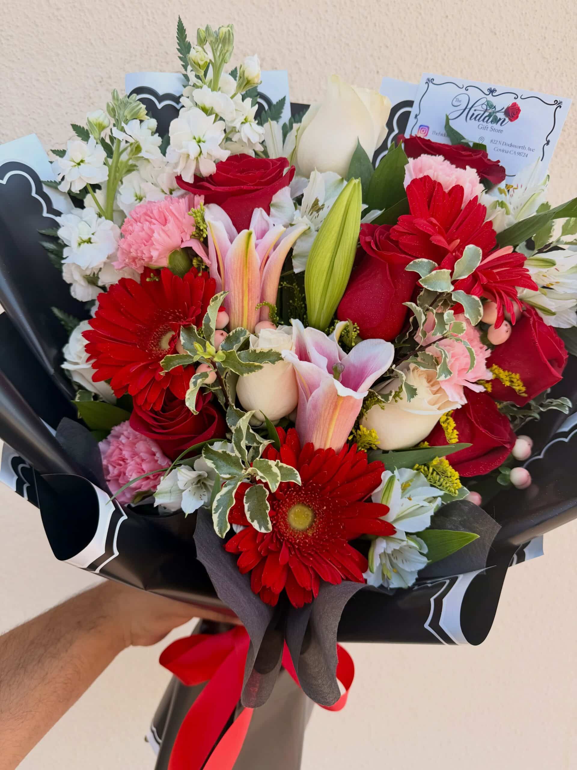 Red, pink, and white floral bouquet with roses, gerbera daisies, lilies, carnations, and greenery