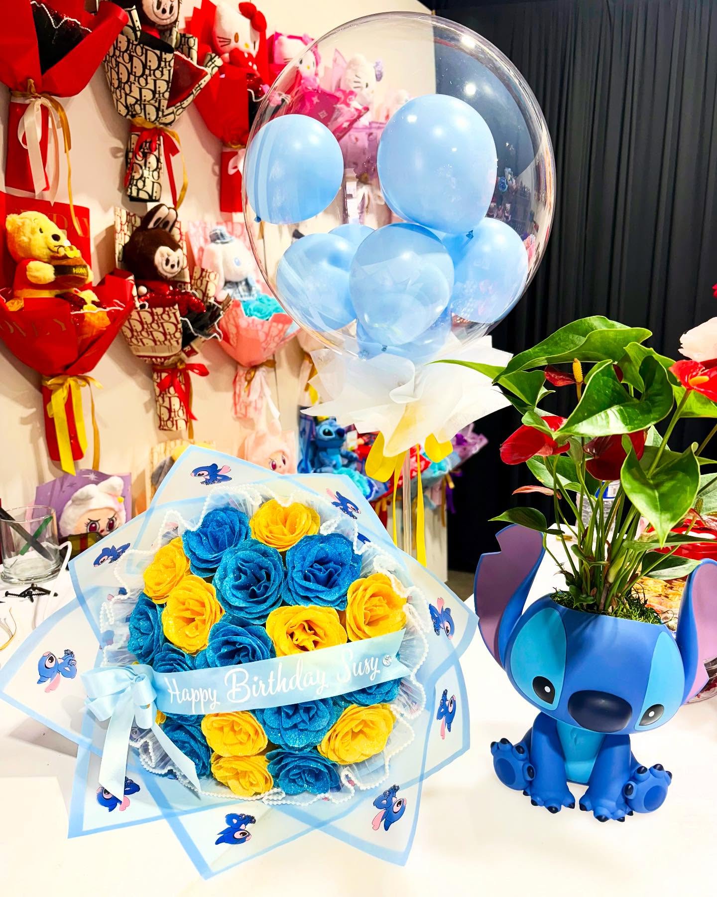 Stitch-themed birthday flower bouquet with blue and yellow roses, balloon arrangement, and Stitch planter