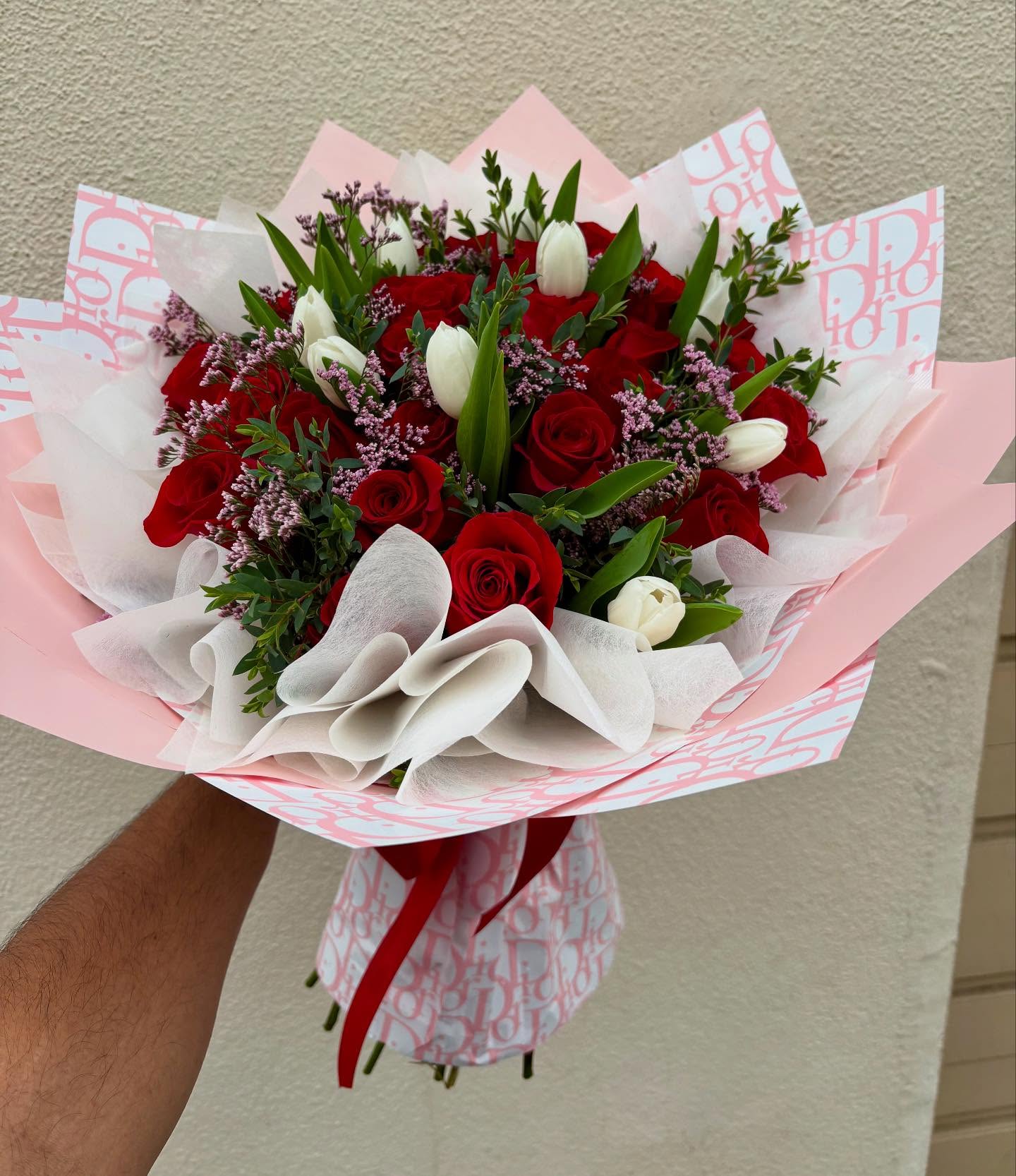 Red rose and white tulip bouquet with greenery and pink decorative wrapping