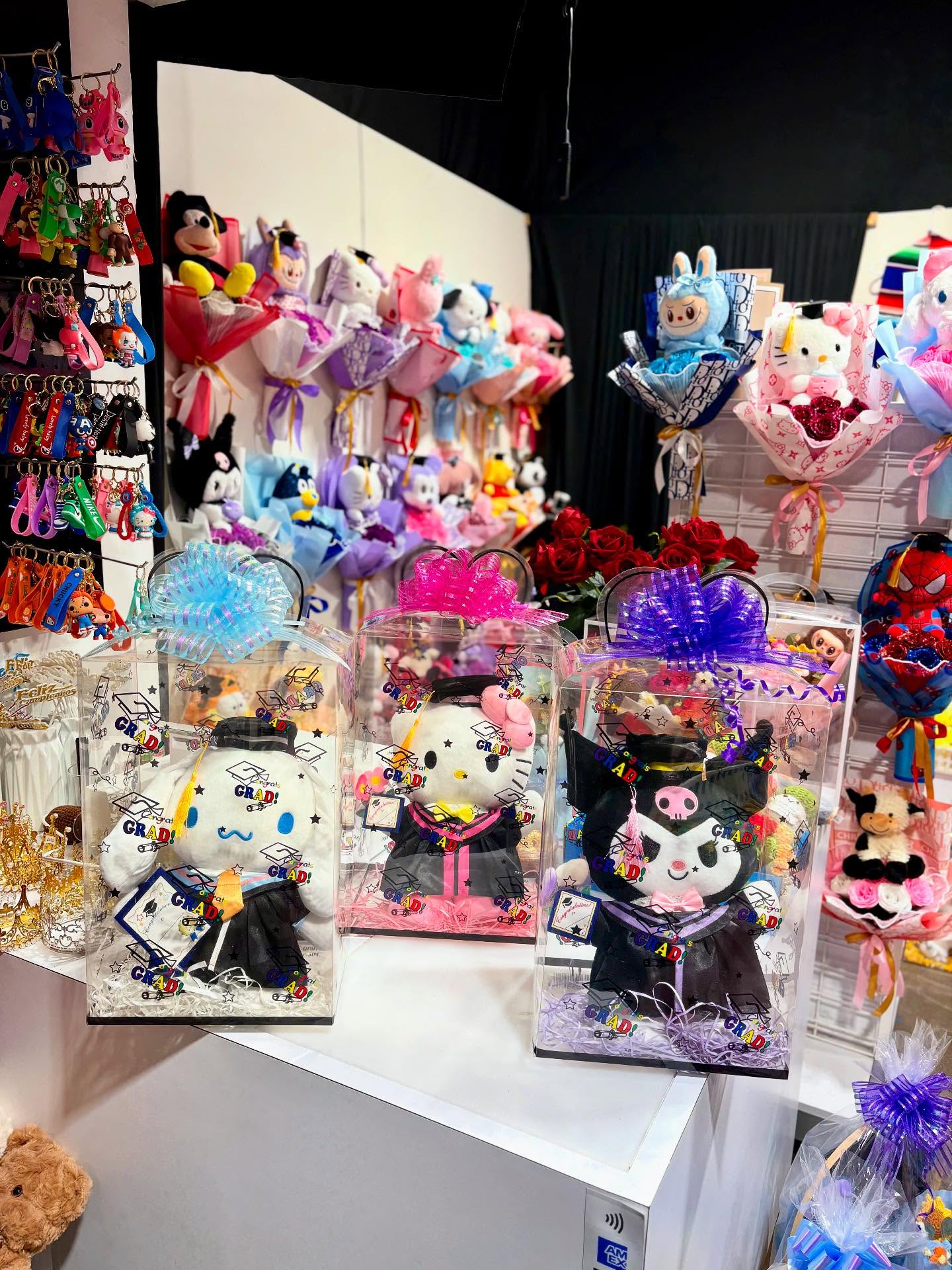 Graduation gift boxes featuring character plush toys dressed in caps and gowns, colorful bows, and festive graduation-themed packaging.