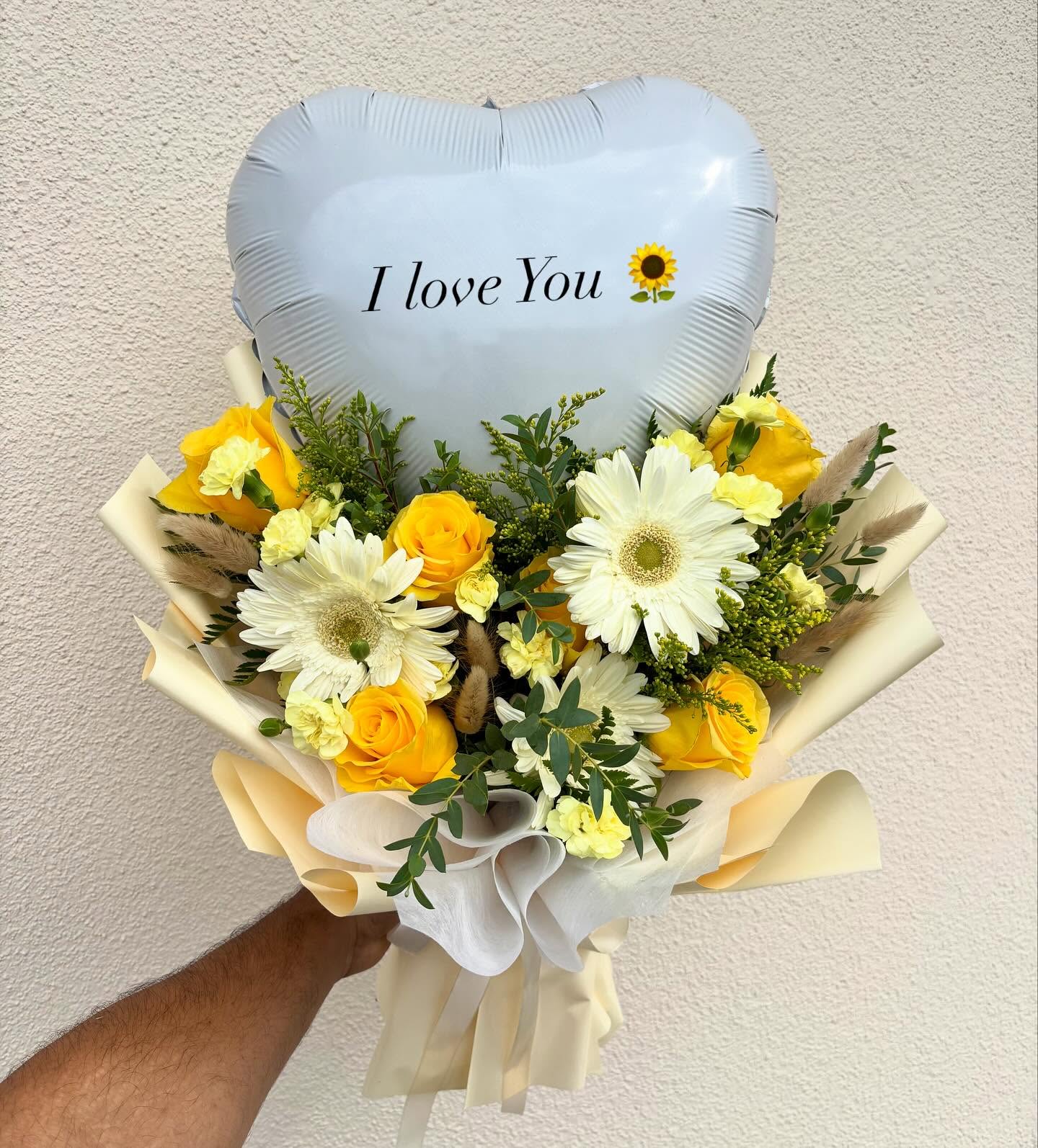 Yellow and white flower bouquet with roses, gerbera daisies, greenery, and an “I Love You” heart balloon