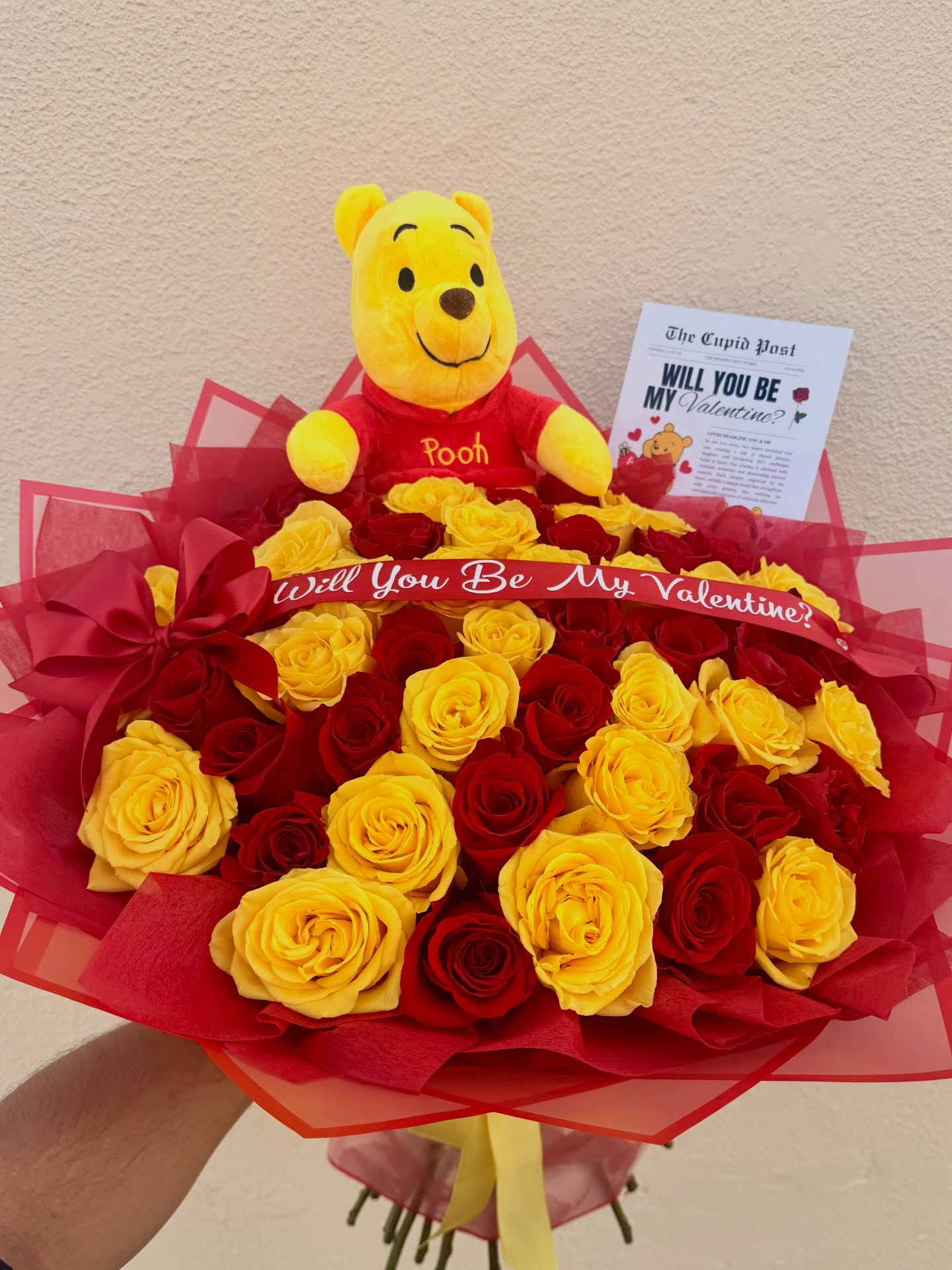 Winnie the Pooh Valentine bouquet with red and yellow roses and a romantic “Will You Be My Valentine?” message