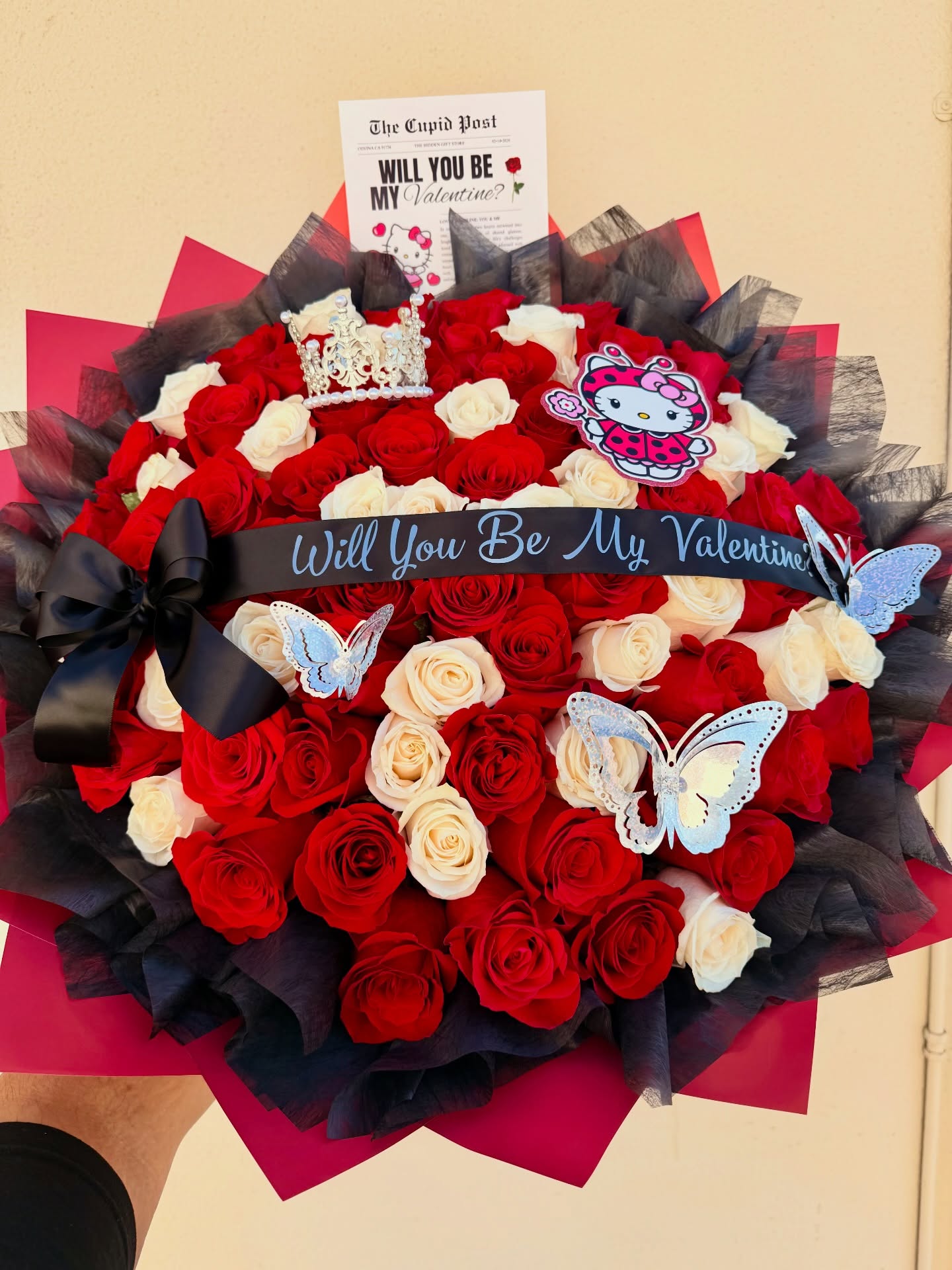 Valentine’s Day bouquet with red and white roses, black ribbon, butterflies, and Hello Kitty decorations