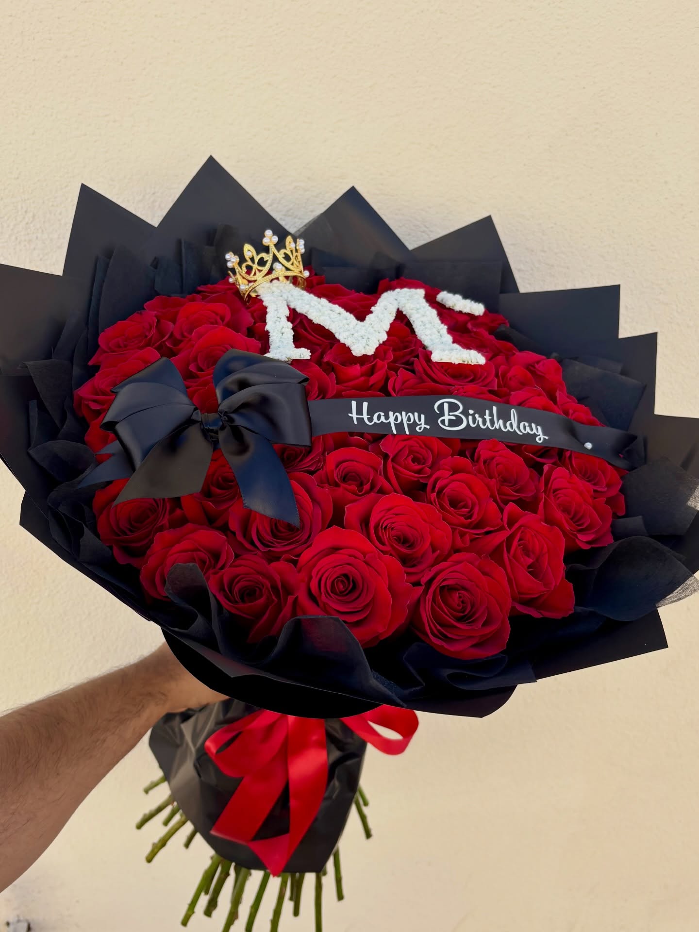 Luxury birthday bouquet of red roses with black wrapping, crown, initial M, and Happy Birthday ribbon