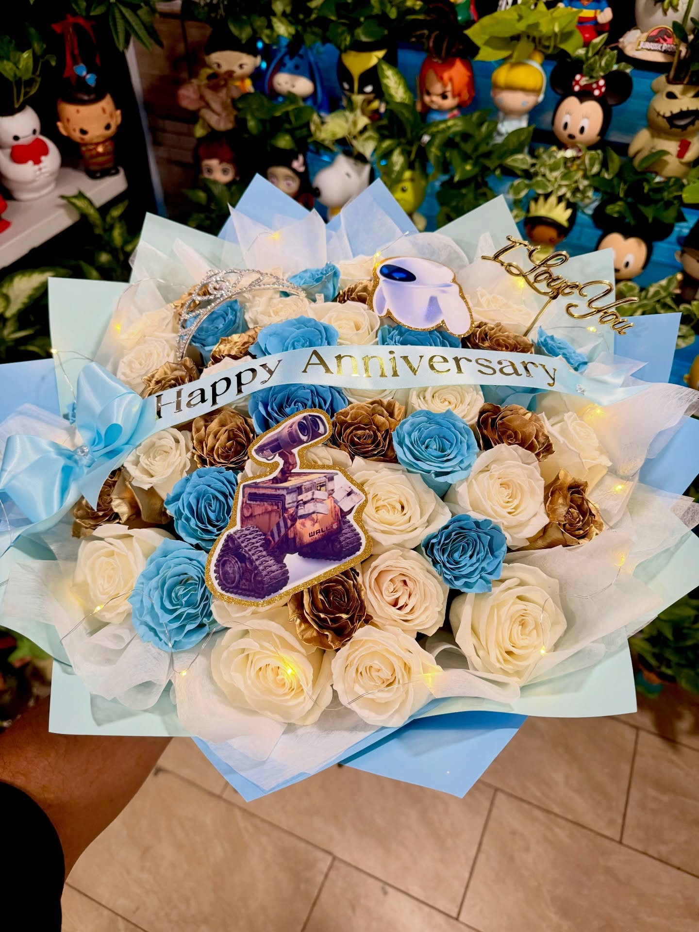 Happy anniversary bouquet with blue, white, and gold roses featuring WALL-E and EVE decorations