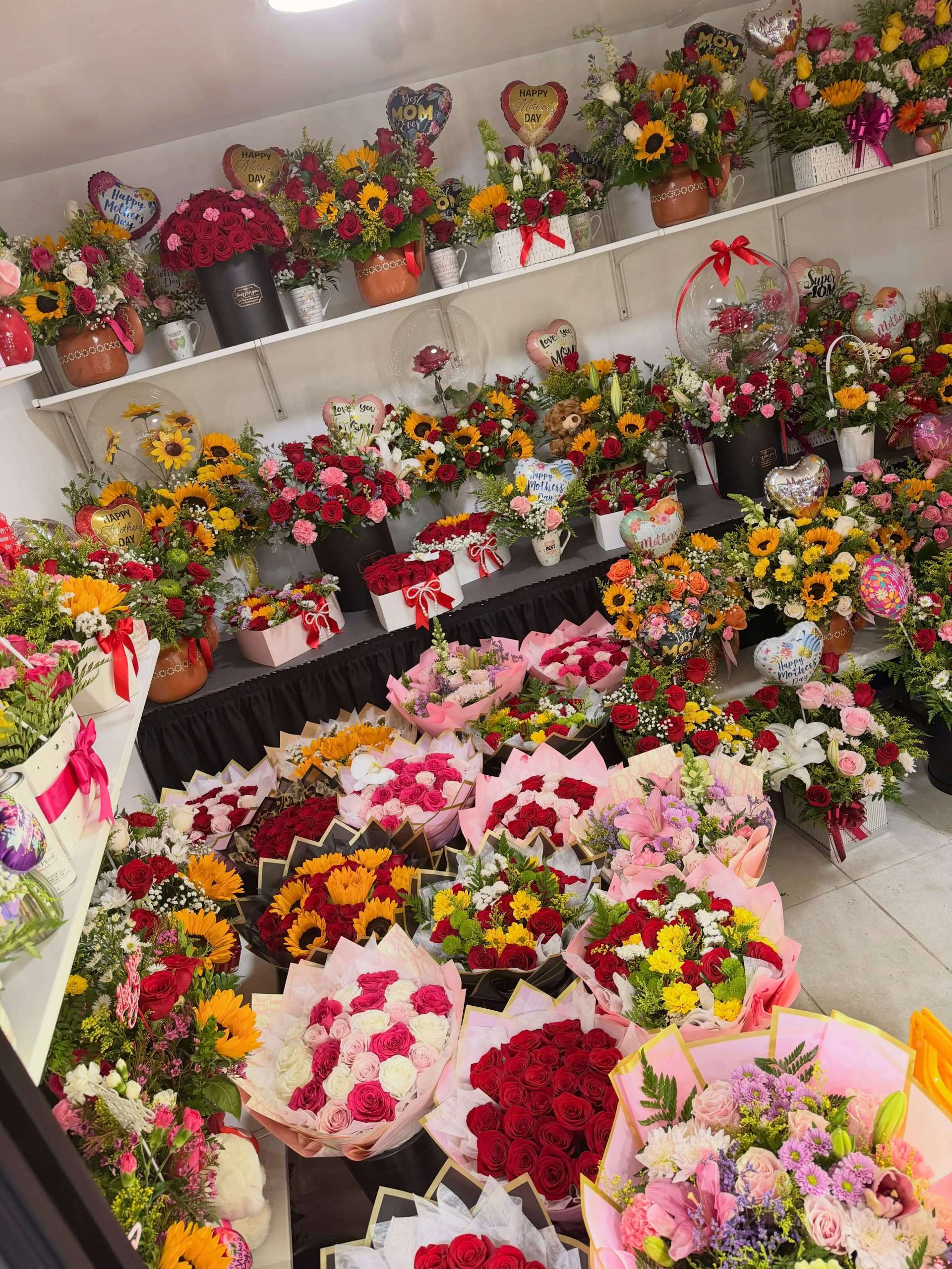 Flower shop display filled with Mother’s Day bouquets featuring roses, sunflowers, lilies, and colorful floral arrangements