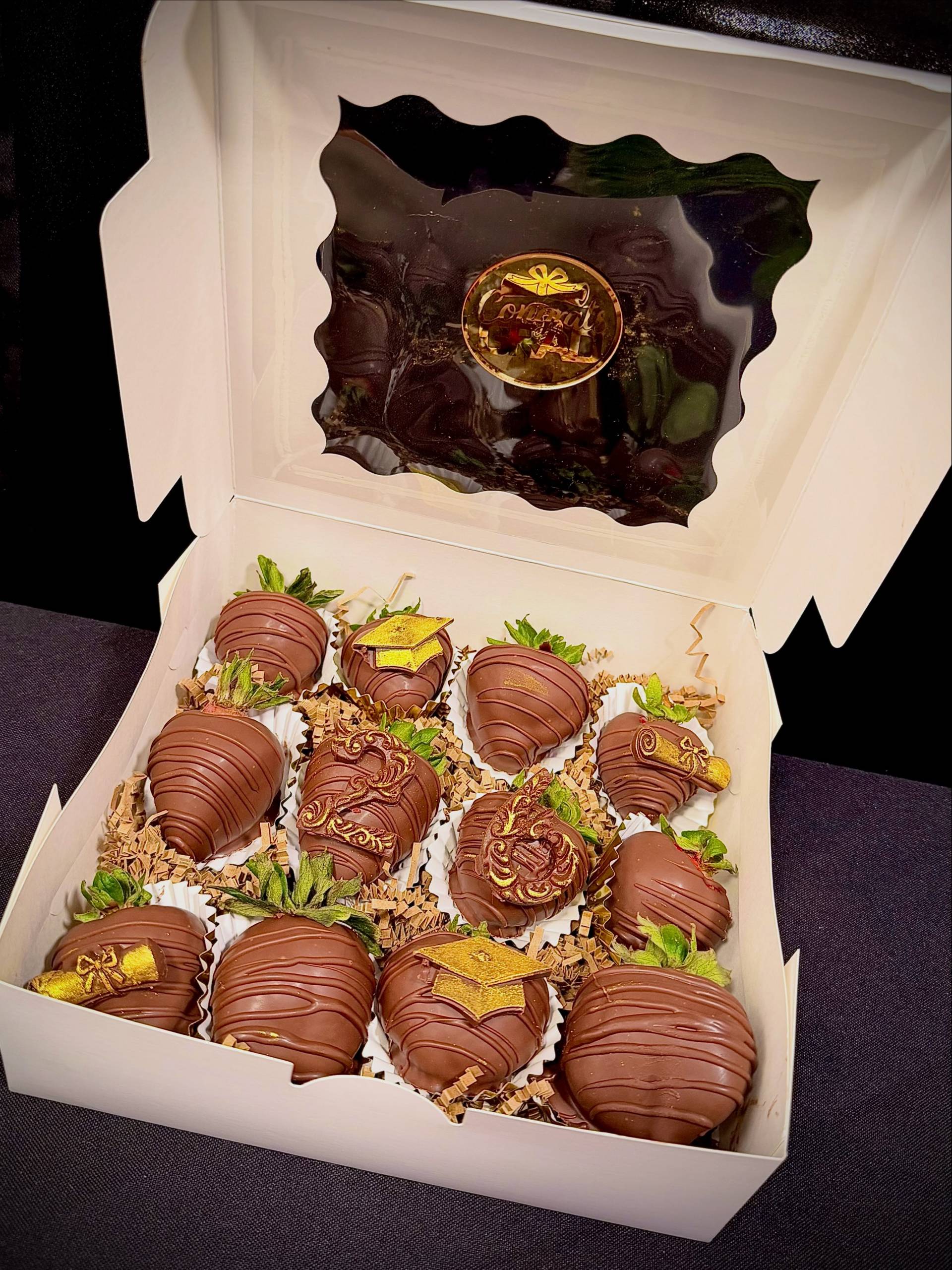 Graduation gift box with chocolate-covered strawberries decorated with gold graduation caps and diplomas