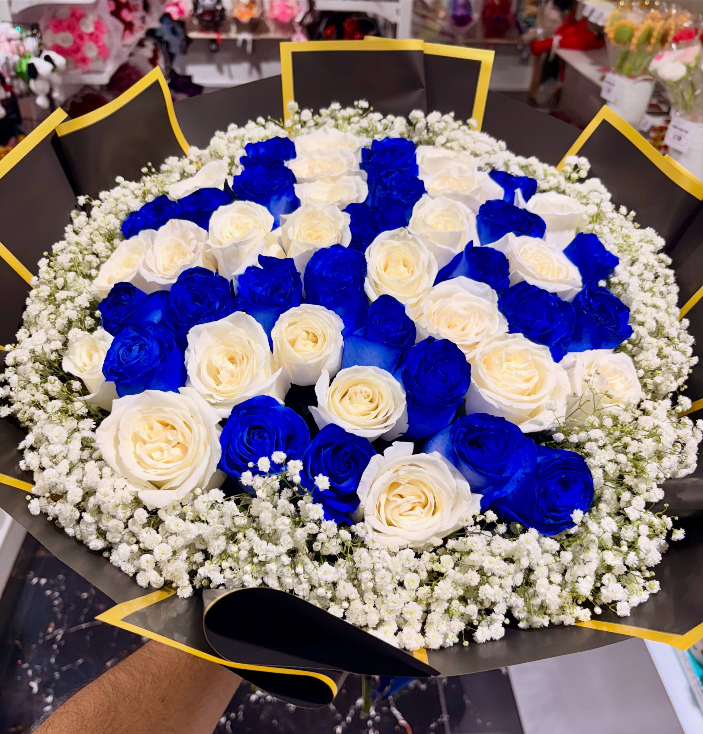 Luxury bouquet of blue and white roses with baby’s breath and black and gold wrapping