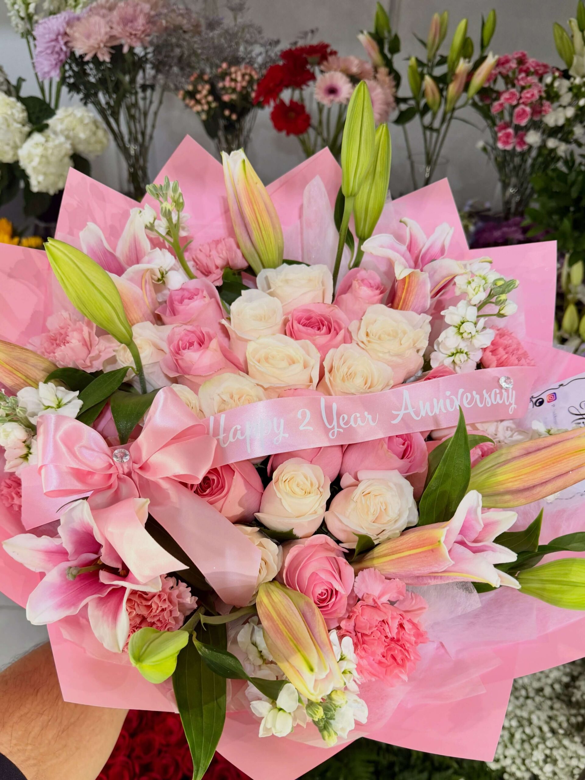 Pink anniversary flower bouquet with roses, lilies, carnations, and a Happy 2 Year Anniversary ribbon