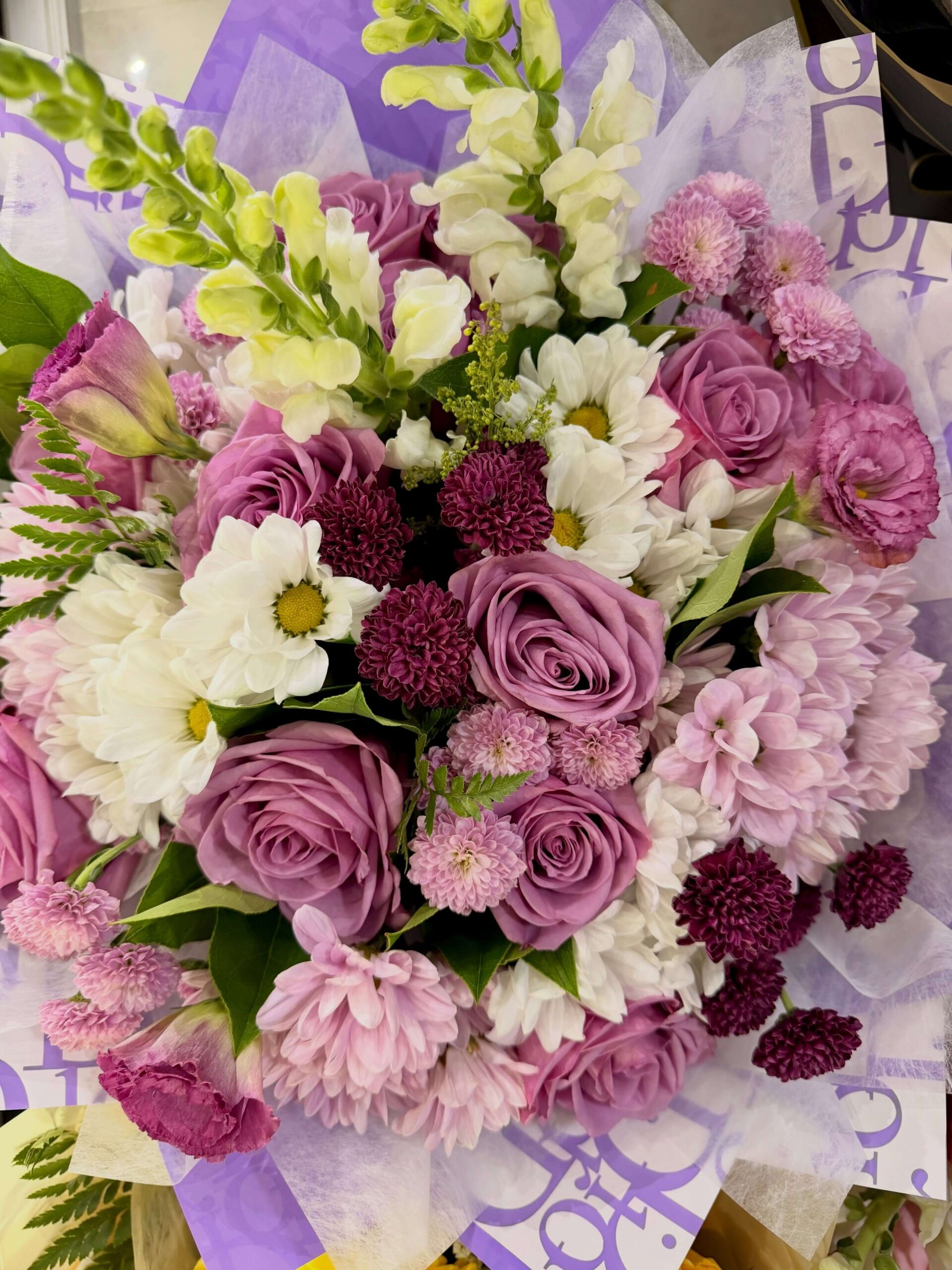 Purple and white floral bouquet with lavender roses, chrysanthemums, daisies, and snapdragons