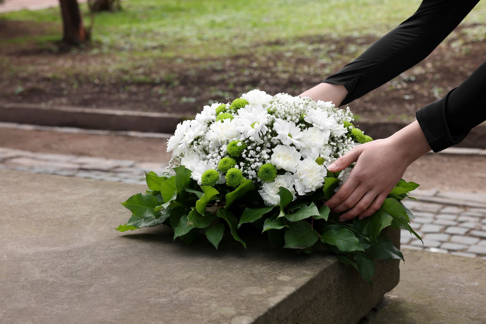 White sympathy floral arrangement with chrysanthemums, carnations, baby's breath, green button mums, and lush greenery