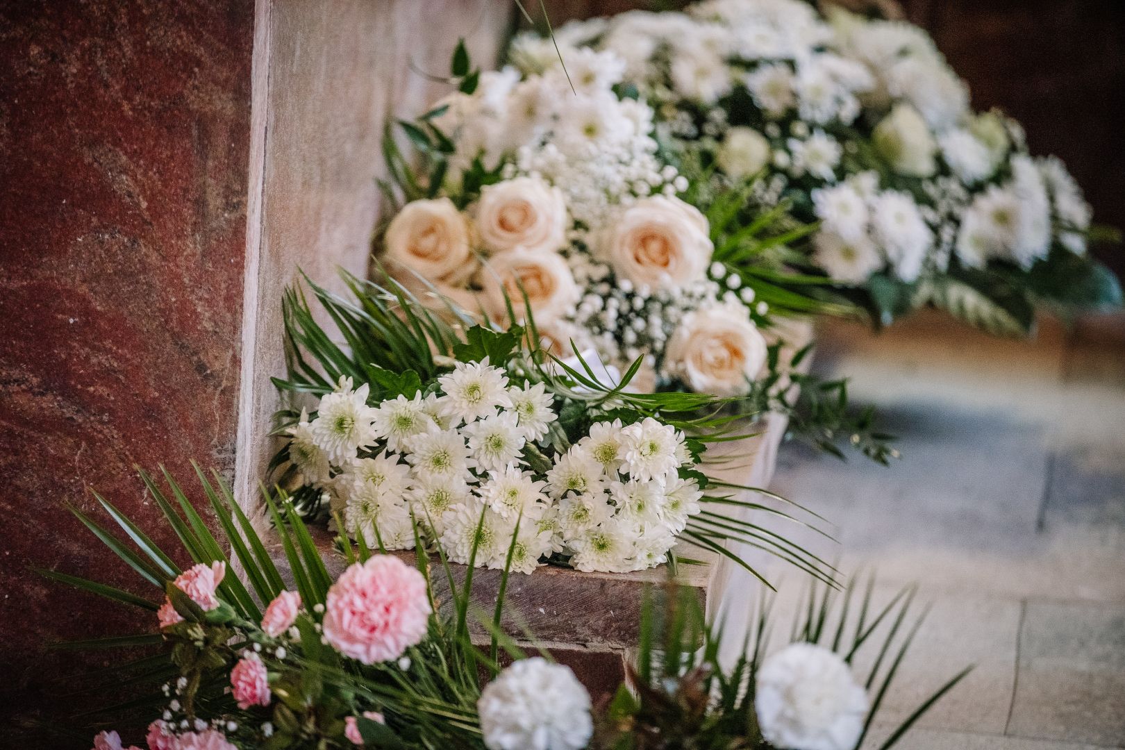 White and blush floral arrangements with roses, chrysanthemums, carnations, baby's breath, and lush greenery